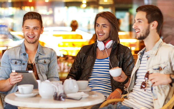 Young hipster guys sitting in a cafe chatting and drinking coffe