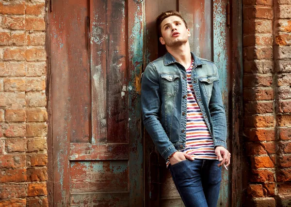 Hipster style guy. Fashion man standing near a wooden door