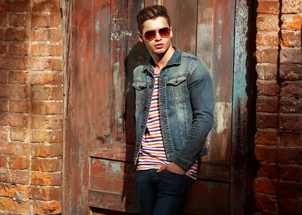 Hipster style guy. Fashion man standing near a wooden door