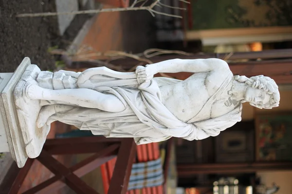 Classical stone sculpture of a young male musician with naked torso and a quiver of arrows