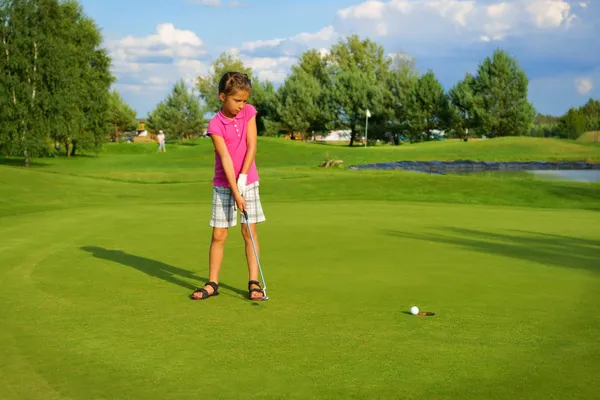 Golf, girl golfer driving ball into the hole