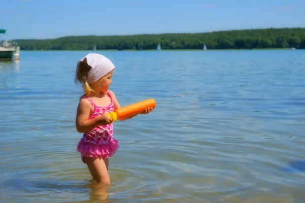 Child, little girl in a pink swim suit and headscarf from water toy
