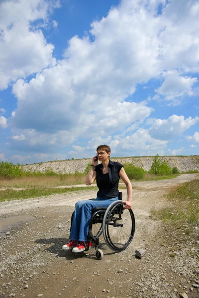 Disabled woman conversing on mobile phone outdoors, path in a quarry