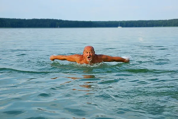 Swimmer, Senior man swimming butterfly strokes. Caucasian male aged 60 years