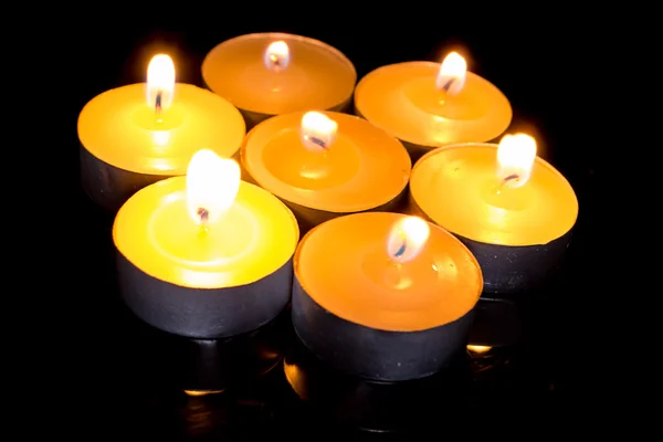 Group of burning candles on black background.