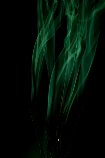 Green smoke rises up on a black background.