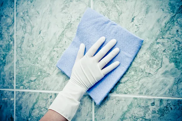Female hand cleaning kitchen tiles with sponge