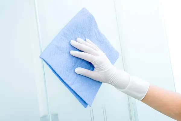 Hand and glove with blue sponge cleaning glass