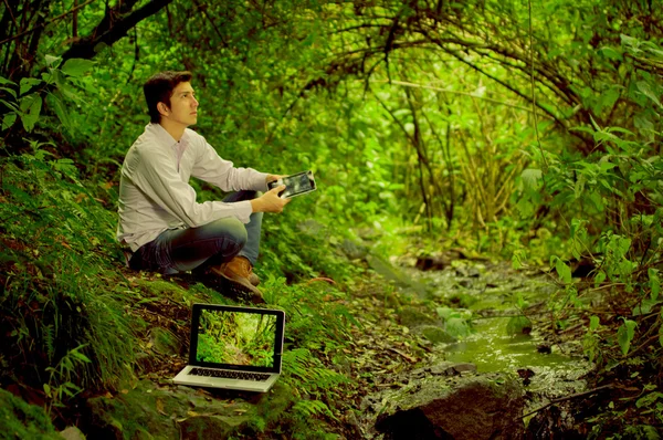 Man using tablet and laptop in the jungle