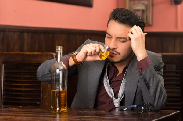 Man in suit drinking alcohol shot