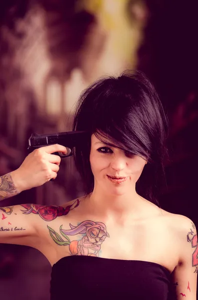 Beautiful tattooed girl with attitude holding gun