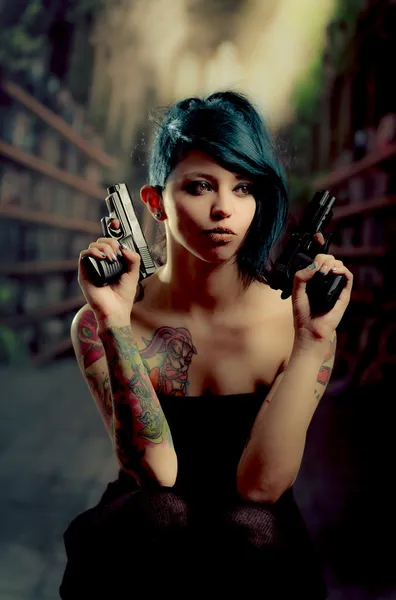 Provocative tattooed girl holding gun