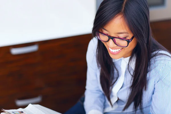 Young happy asian businesswoman reading newspaper