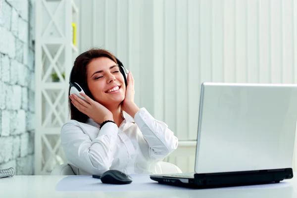 Businesswoman listening music in headphones