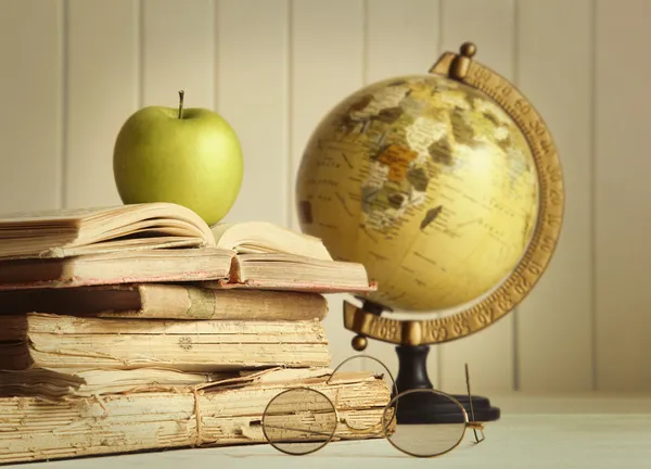 Old books with apple and globe