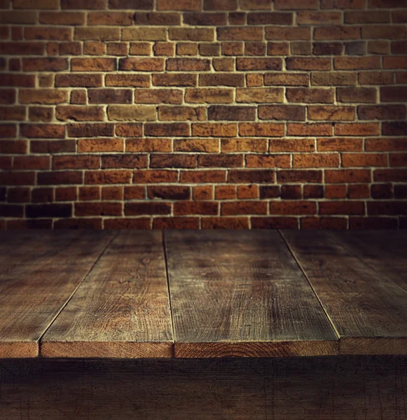 Old wooden table with brick background