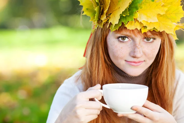 Young redhead teenager woman in a wreath of maple leaves with cu