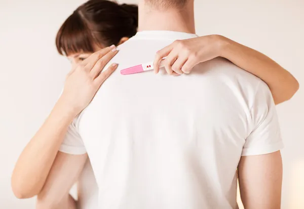 Woman with pregnancy test hugging man