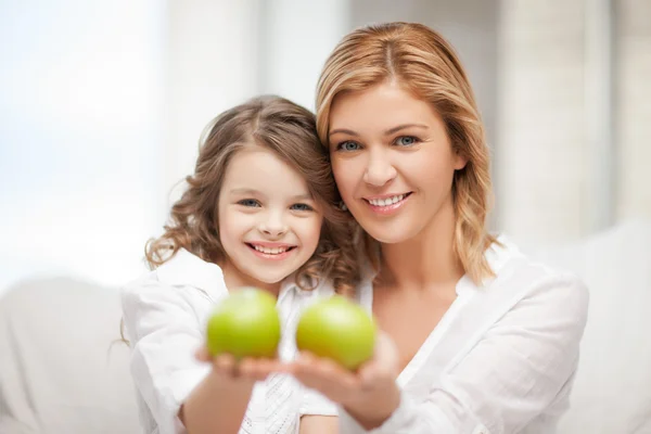 Mother and daughter holding green apples