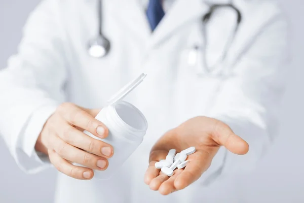 Doctor hands holding white pack and pills