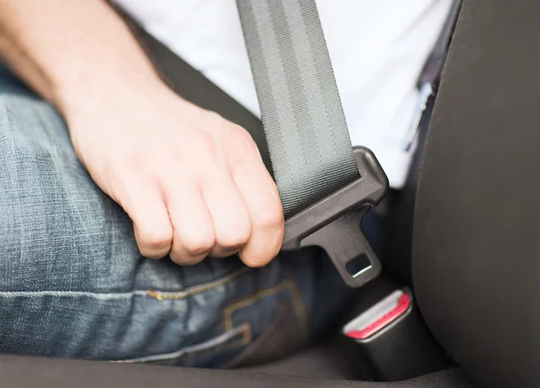 Man fastening seat belt in car