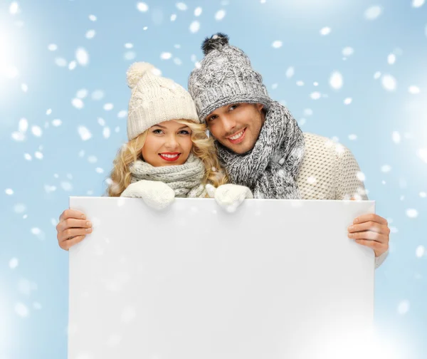 Couple in a winter clothes holding blank board