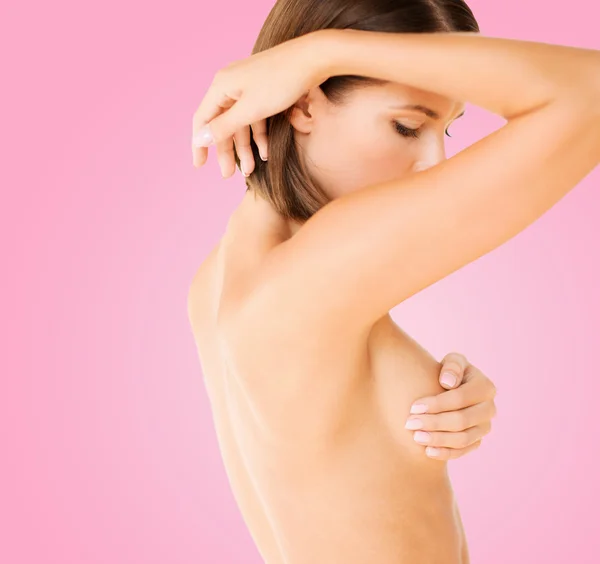 Woman checking breast for signs of cancer
