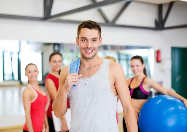 Smiling man standing in front of the group in gym