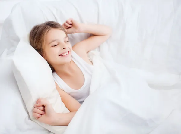 Smiling girl child waking up in bed at home