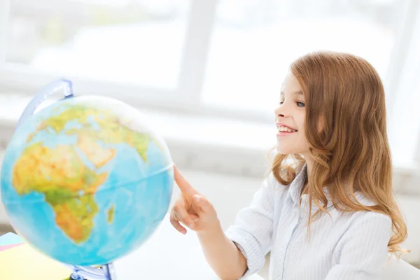 Smiling student girl with globe at school