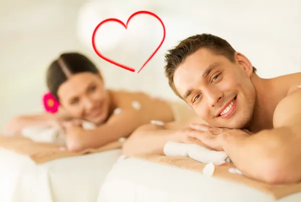 Smiling couple lying on massage table in spa salon