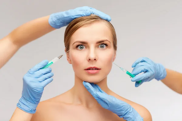 Woman face and beautician hands with syringe