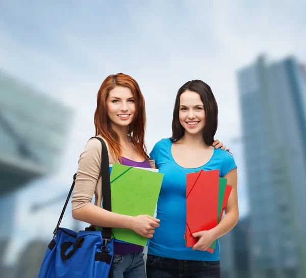 Two smiling students with bag and folders