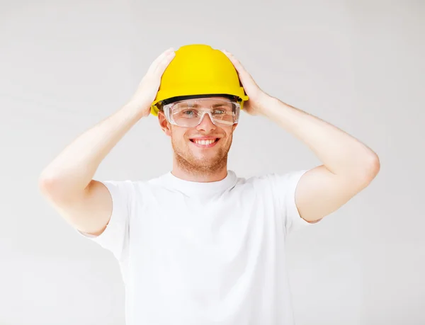 Male builder in safety glasses and yellow helmet