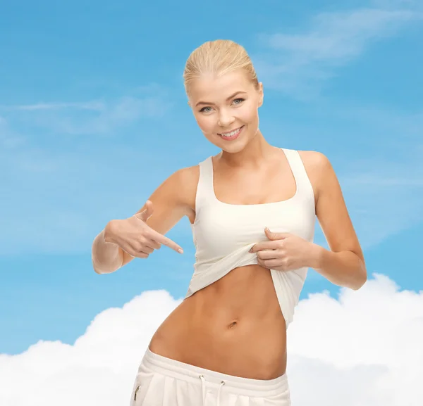 Beautiful sporty woman pointing at her abs