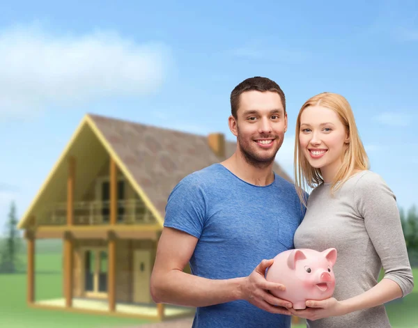 Smiling couple holding big piggy bank