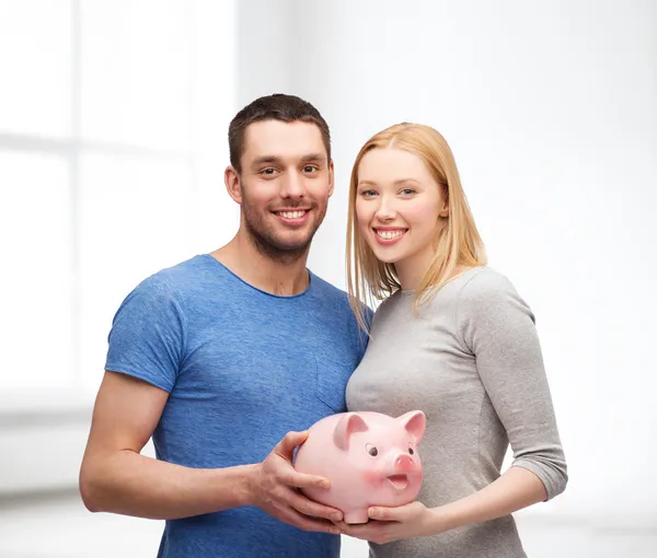 Smiling couple holding big piggy bank