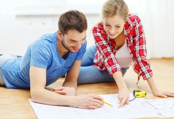 Smiling couple looking at blueprint at home