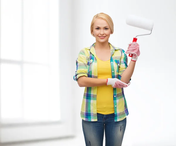 Smiling woman in gloves with paint roller