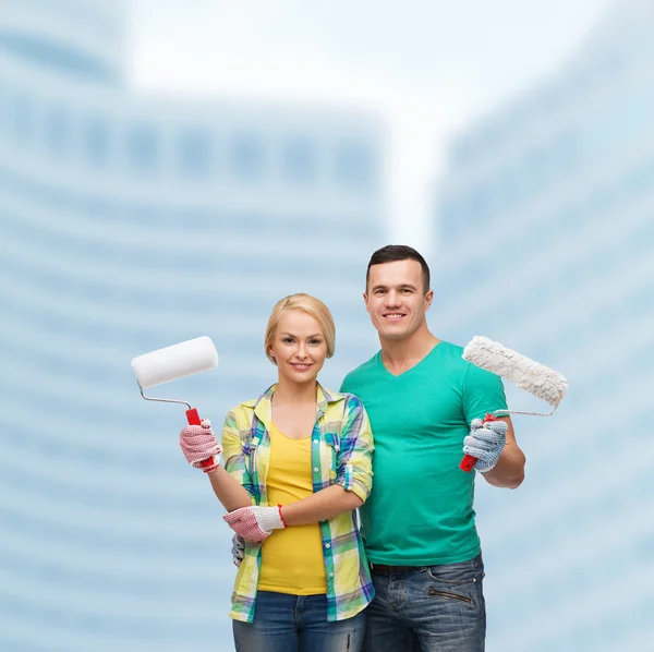 Smiling couple in gloves with paint rollers