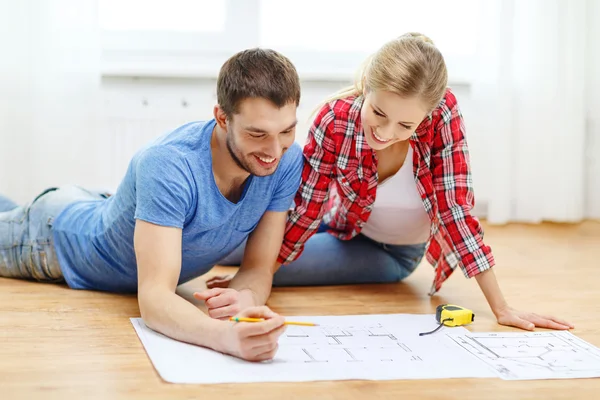 Smiling couple looking at blueprint at home