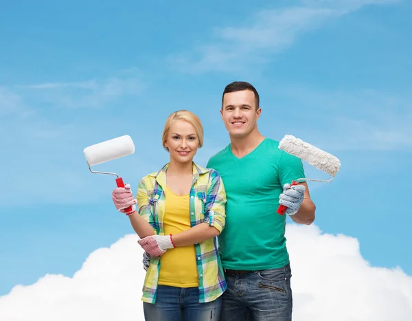 Smiling couple in gloves with paint rollers