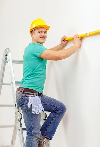 Smiling man building using spirit level to measure