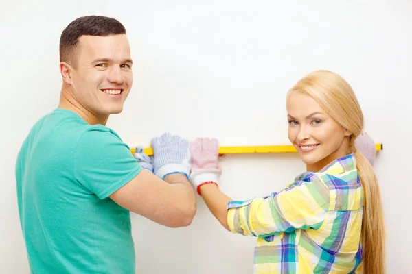 Couple building using spirit level to measure