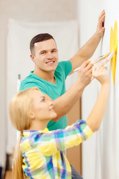 Smiling couple painting small heart on wall