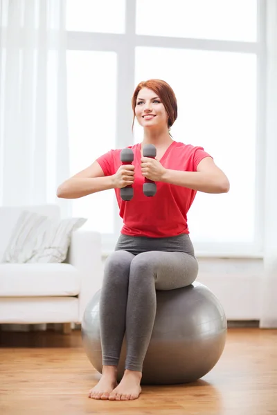 Smiling redhead girl exercising with fitness ball