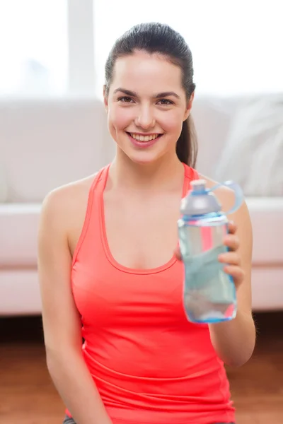 Smiling girl with bottle of water after exercising