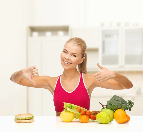 Woman with fruits and hamburger comparing food