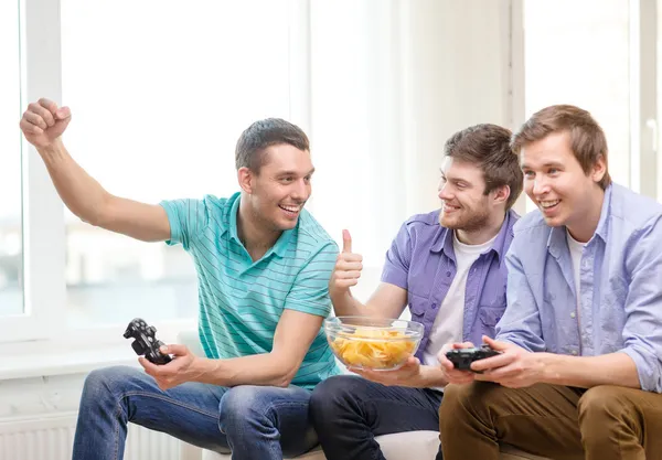 Smiling friends playing video games at home