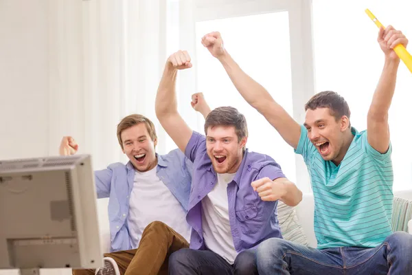 Happy male friends with vuvuzela watching sports